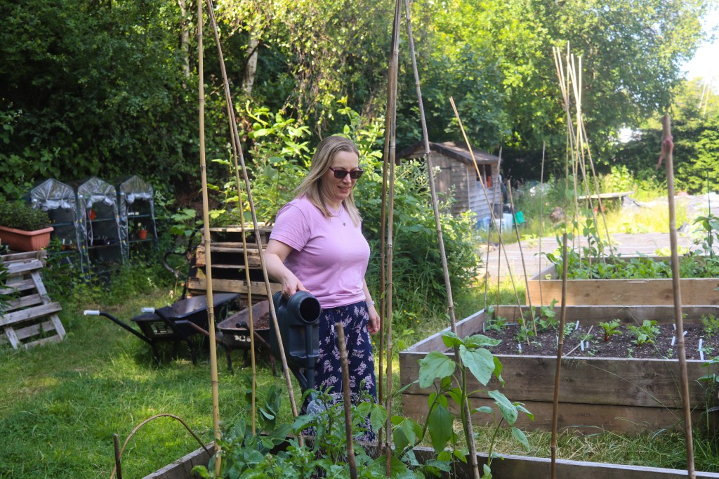 Susan watering her vegetables in the raised bed