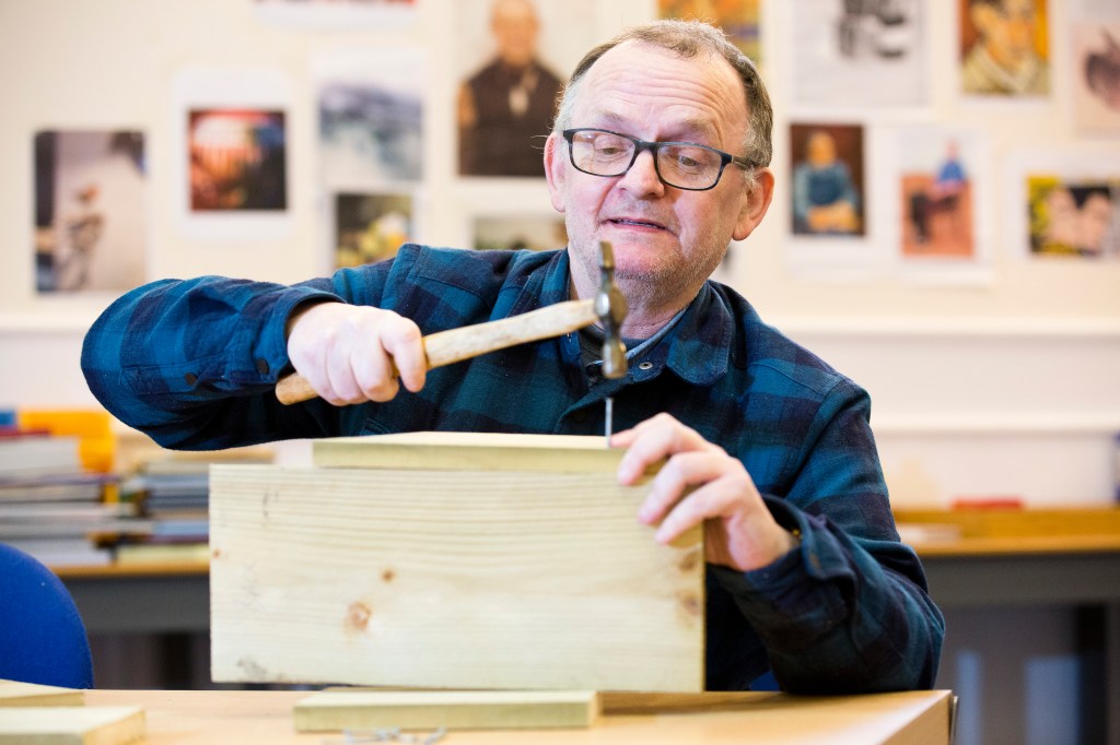 Steve taking part in a woodwork activity, using a hammer.