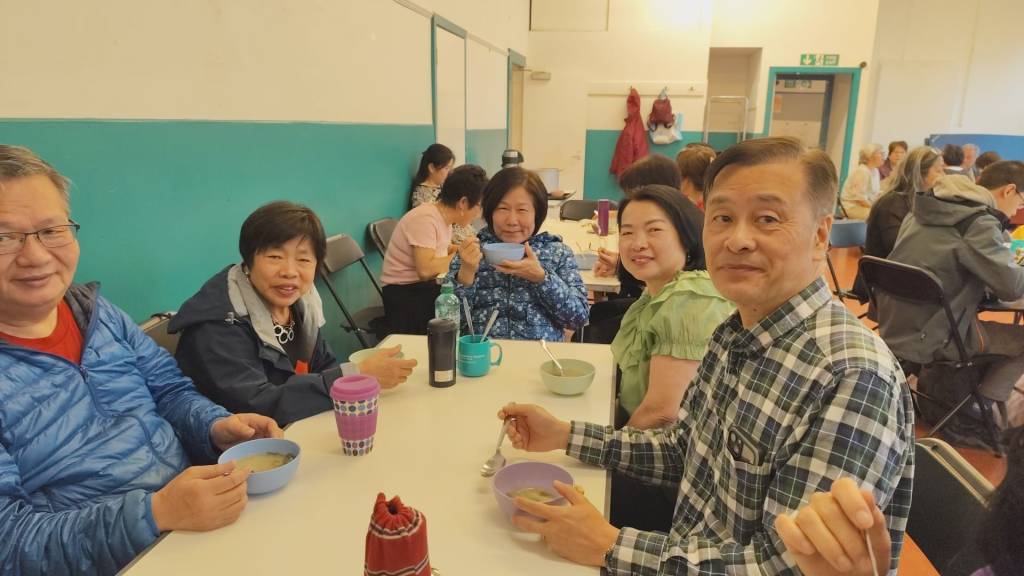 A group of people sit around a table eating food together.