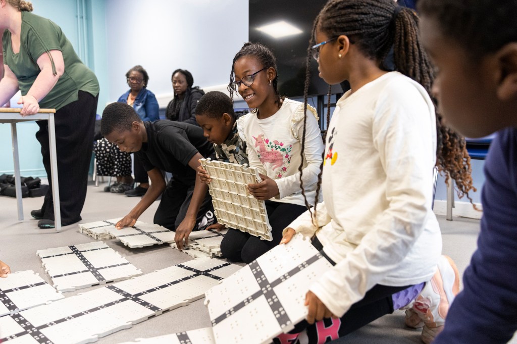 young people smiling as they work together to build the base for where the robot will operate.