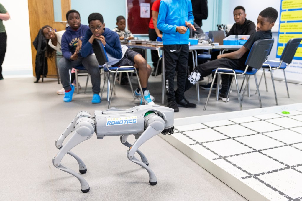 The Unitree go2 pro robot in action, the young people curiously watch in the background